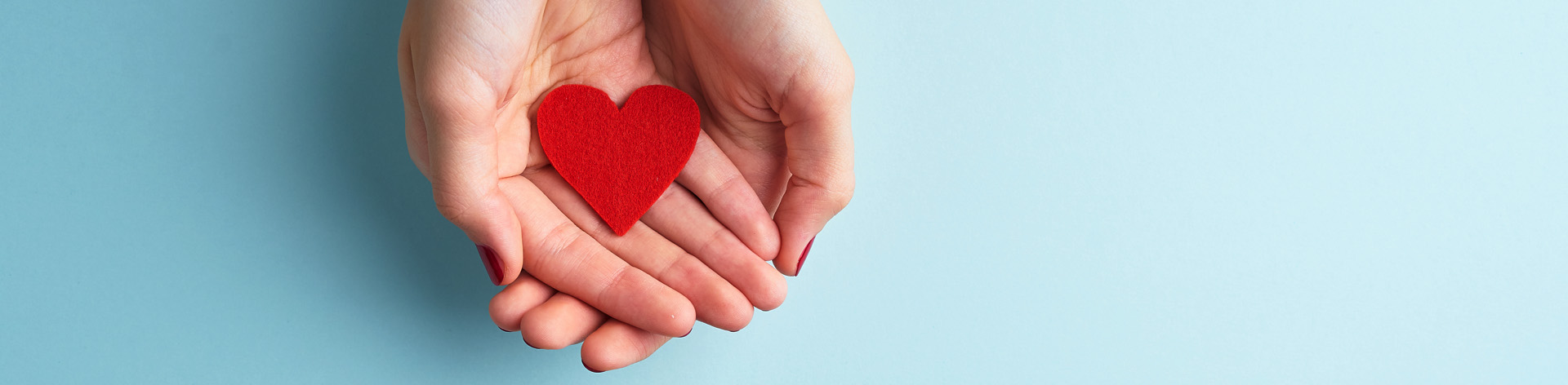 Hands holding a fabric heart.